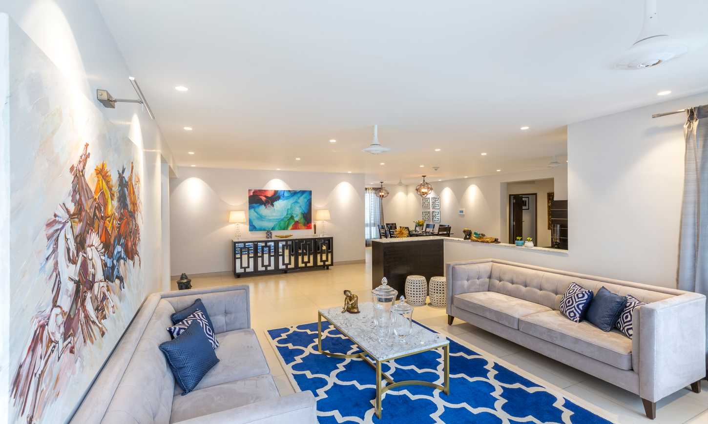 A modern living room with sofas and royal blue carpet by luxury interior designers in bangalore